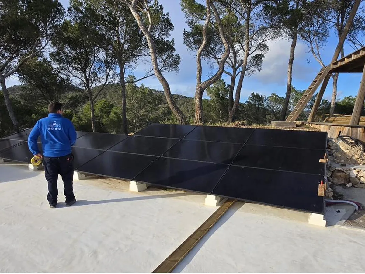 Gran instalación fotovoltaica con técnico revisando paneles solares en una propiedad de Mallorca